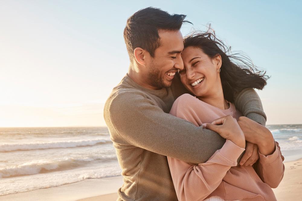 Man and woman smiling and embracing on the beach, charlotte nc