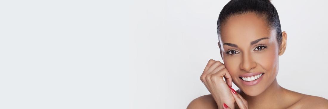 beautiful black woman hair tied back and red painted nails smiling against a white background
