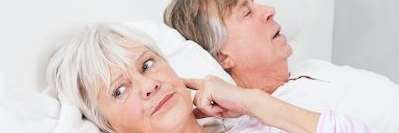 Older woman plugging her ear to block husbands snoring, charlotte north carolina