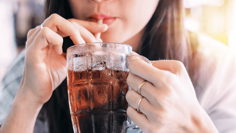 Woman drinking a coke out of a glass with a straw, charlotte nc