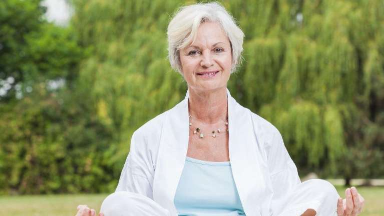 A woman sitting cross legged in the grass | holistic dentist Charlotte NC