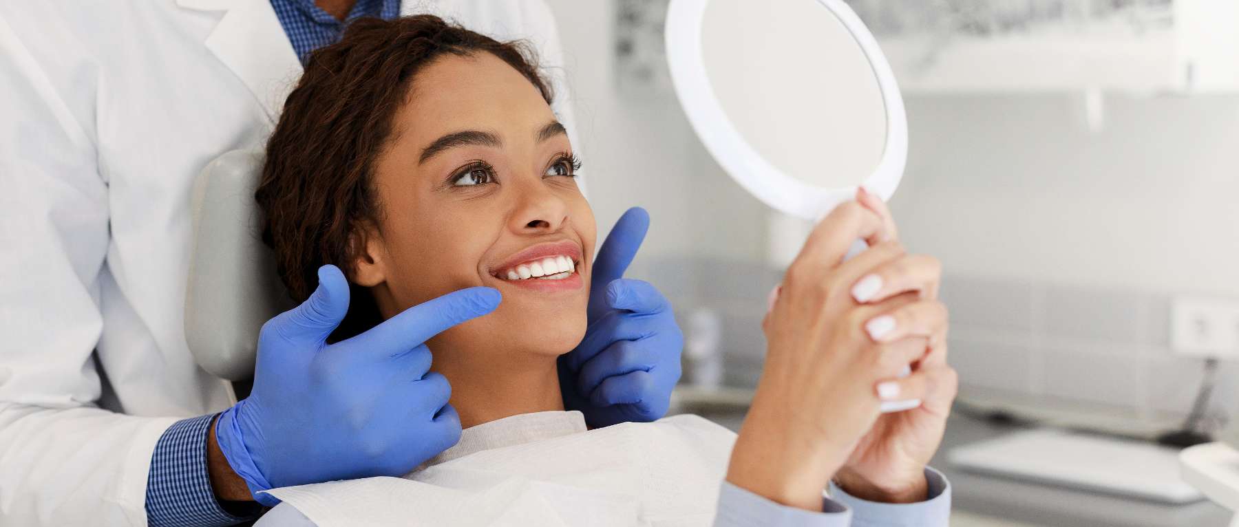 Black woman holding a mirror looking at her teeth, charlotte nc